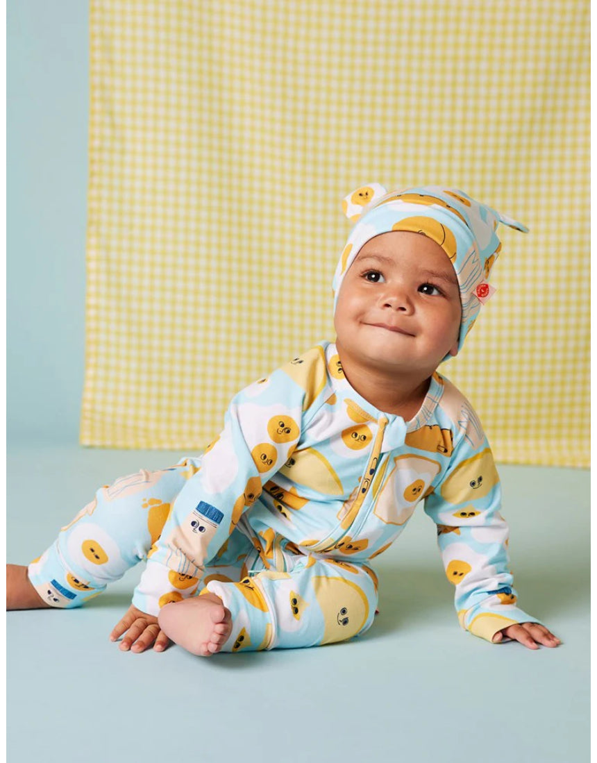 Baby wearing a Halcyon Nights Brunch Buddies long sleeve zip suit with a matching hat, featuring colorful brunch-themed patterns.