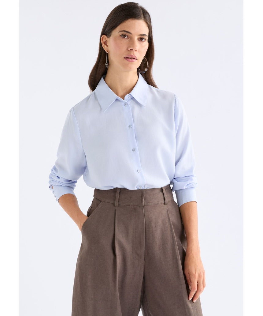 Pale blue Tettu shirt by ELK The Label, a stylish women's top with soft fabric and classic fit, displayed on a hanger.