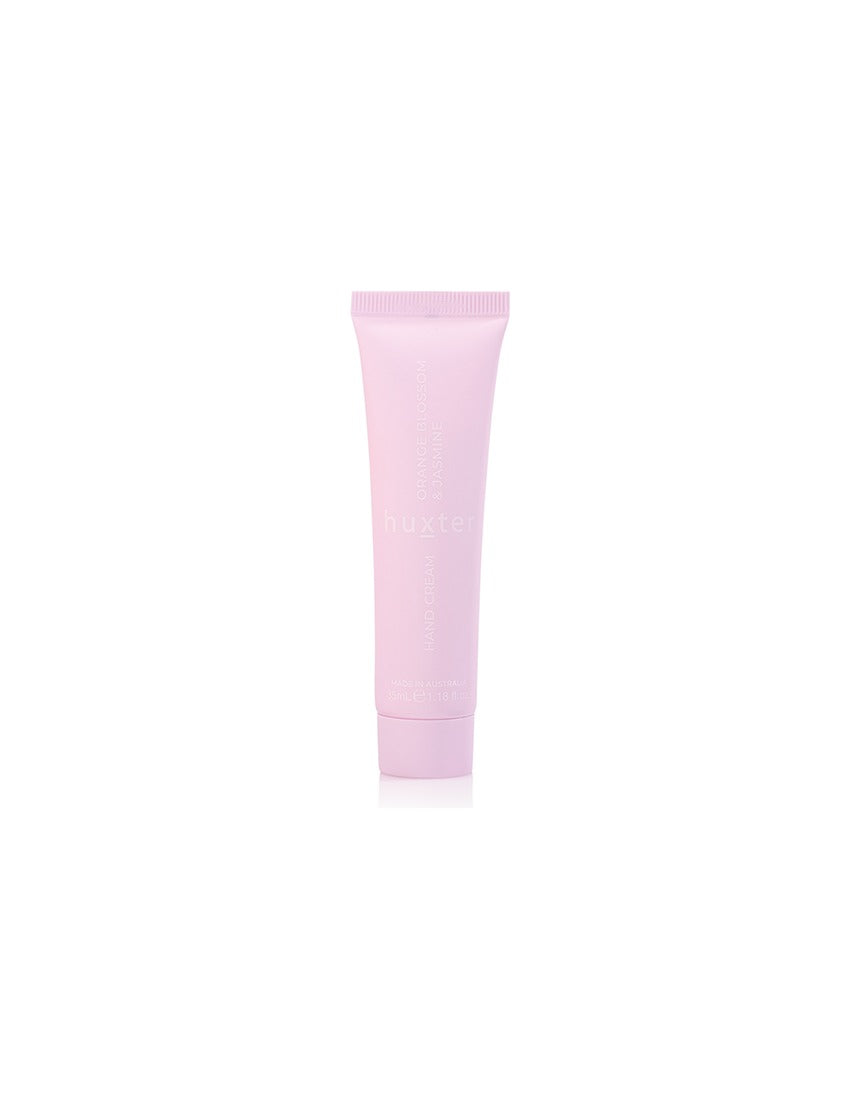Huxter Adorned Christmas hanging hand cream in soft pink with festive design, displayed on a decorative surface.