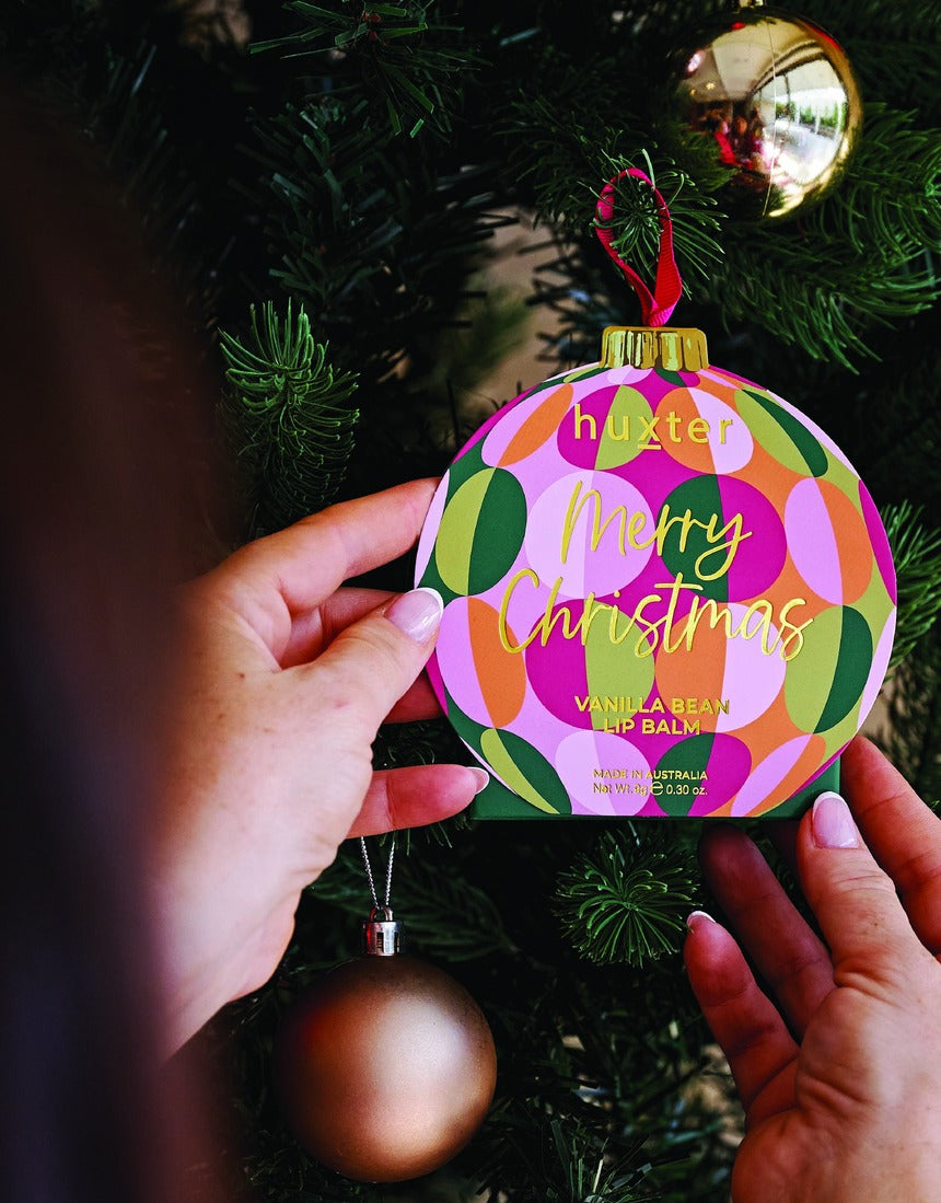 Huxter Adorned Christmas Hanging Lip Balm in green, featuring festive packaging with holiday-themed design and branding.