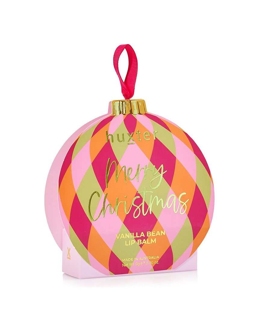 Huxter Adorned Christmas Hanging Lip Balm in soft pink, decorative holiday packaging, hanging with festive decorations.