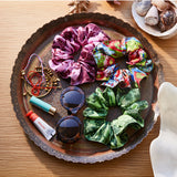 Sage x Clare Delphine silk scrunchie set with three elegant, shiny fabric hair accessories on a neutral background.