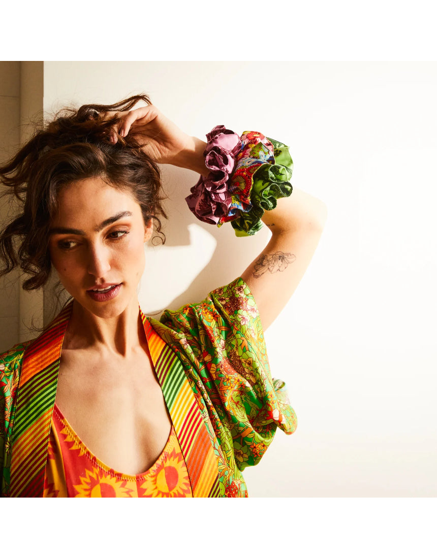 Set of Sage x Clare Delphine silk scrunchies featuring vibrant, patterned fabrics on a neutral background.