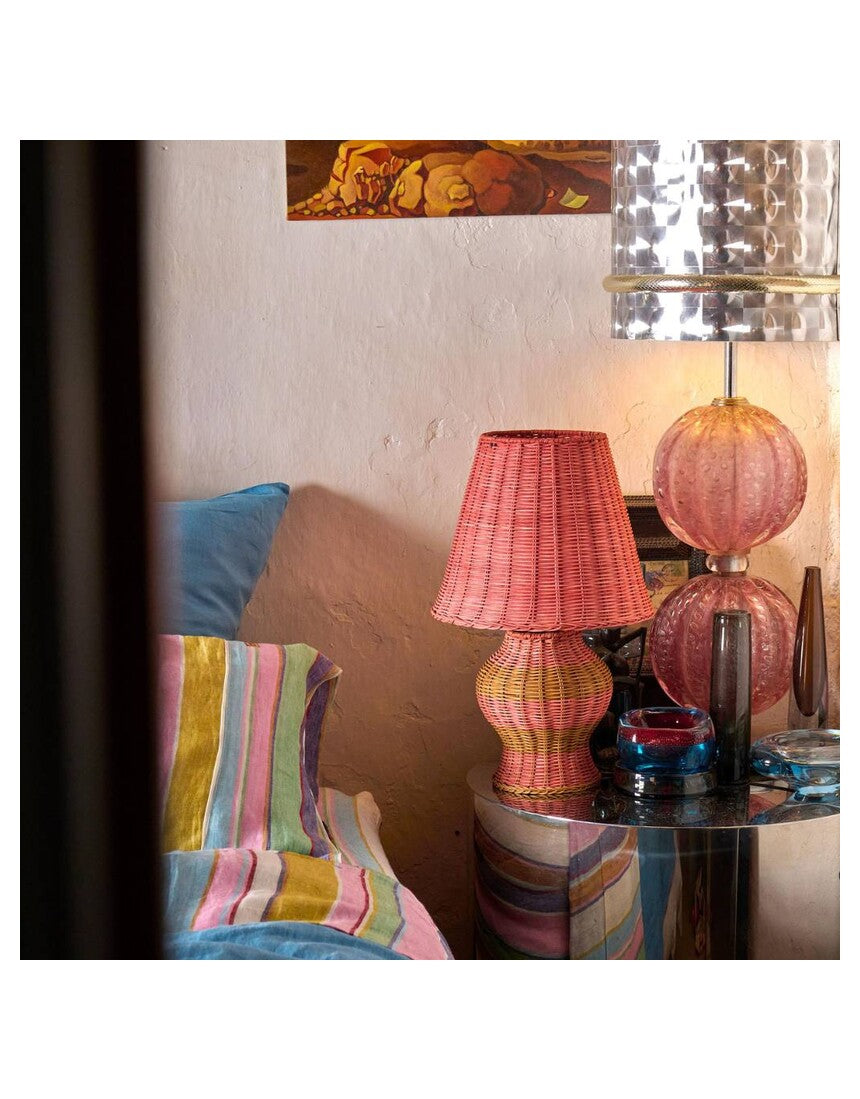 Kip & Co Guava Stripe Le Parisian Rattan Table Lamp with woven rattan base and fabric striped lampshade on a wooden table
