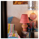 Kip & Co Guava Stripe Le Parisian Rattan Table Lamp with woven rattan base and fabric striped lampshade on a wooden table