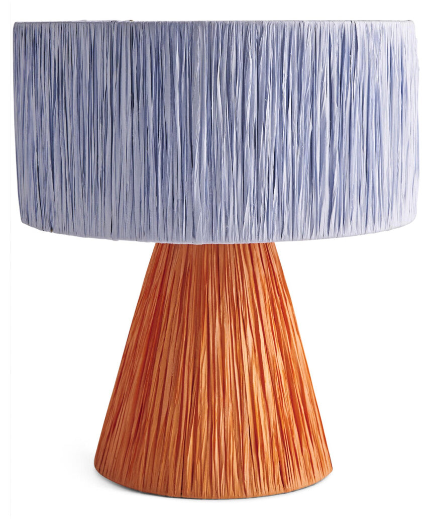 Kip & Co Tangier Raffia Table Lamp with woven rattan base and beige fabric shade on a wooden side table.
