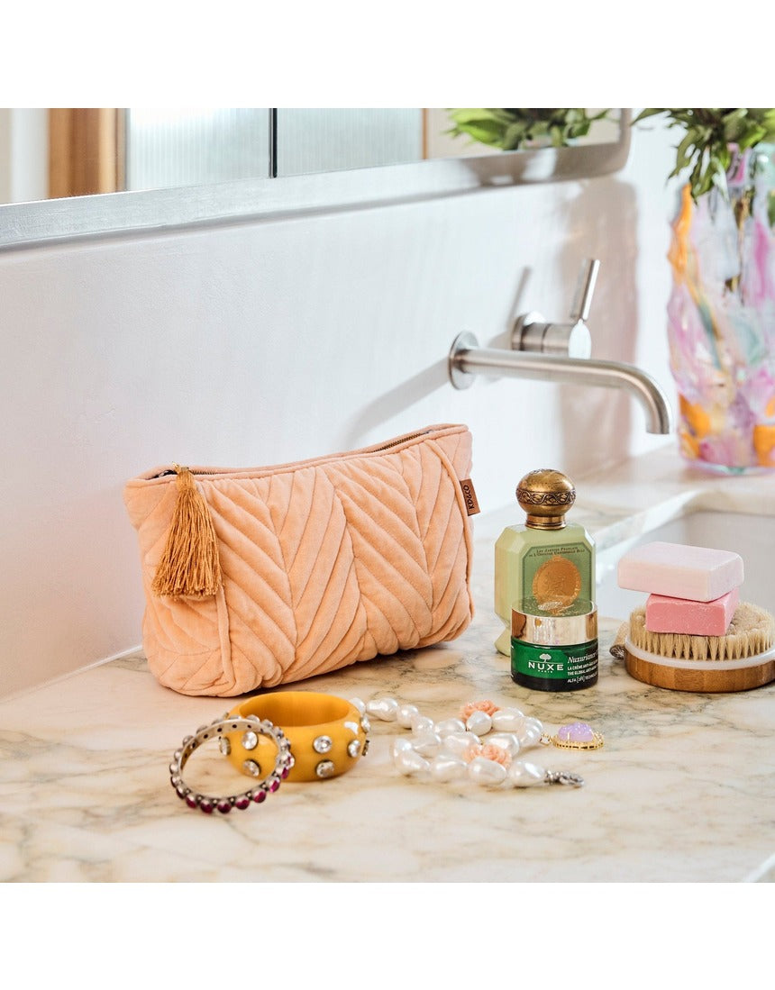 Kip&Co velvet toiletry bag in vibrant melon color with a soft fabric texture and zipper closure.