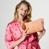 Kip&Co velvet toiletry bag in a vibrant melon color, with a soft texture and compact design for travel organization.