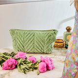 Kip&Co velvet toiletry bag in pesto green with a soft, plush texture, featuring a zip closure and compact design for travel toiletries.