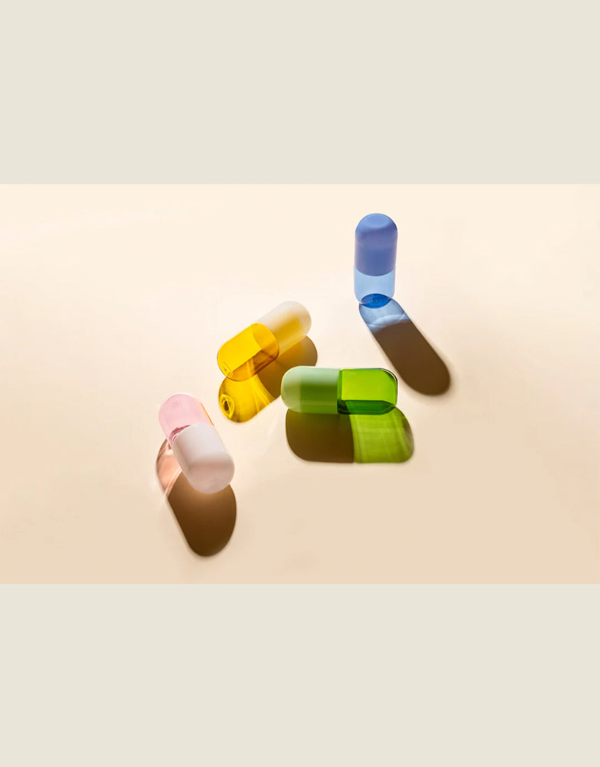 Maho Happi Pill glassware set featuring blue pill-shaped glasses on a white surface with decorative elements.