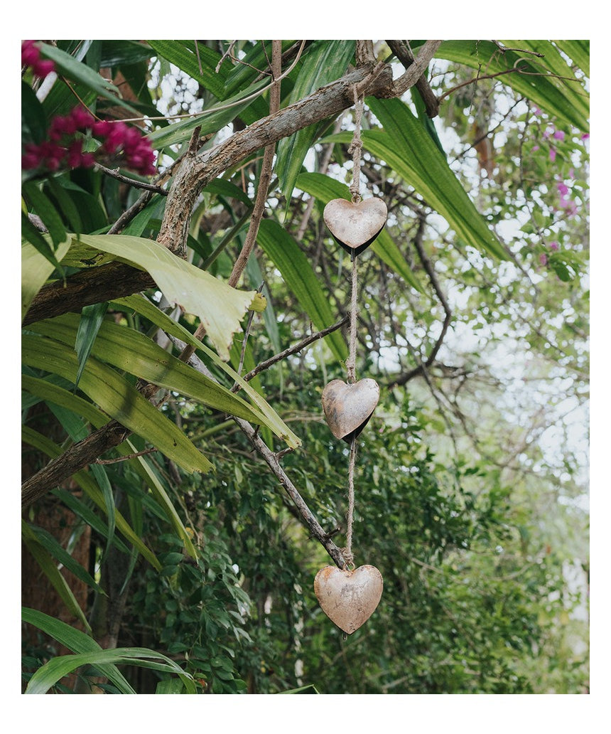 Matr Boomie Alaya Heart Trio Wind Chime with three hanging metal hearts and intricate design, hanging outdoors.