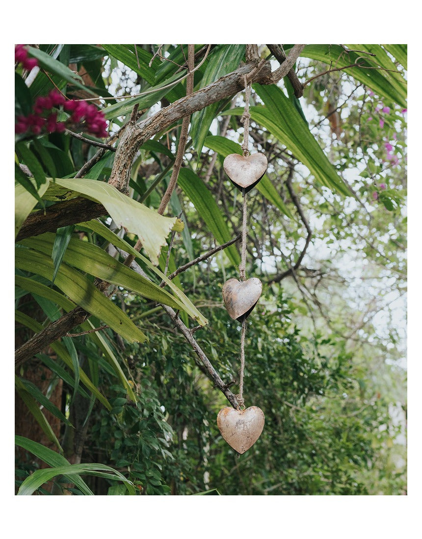 Matr Boomie Alaya Heart Trio Wind Chime with three hanging metal hearts and intricate design, hanging outdoors.