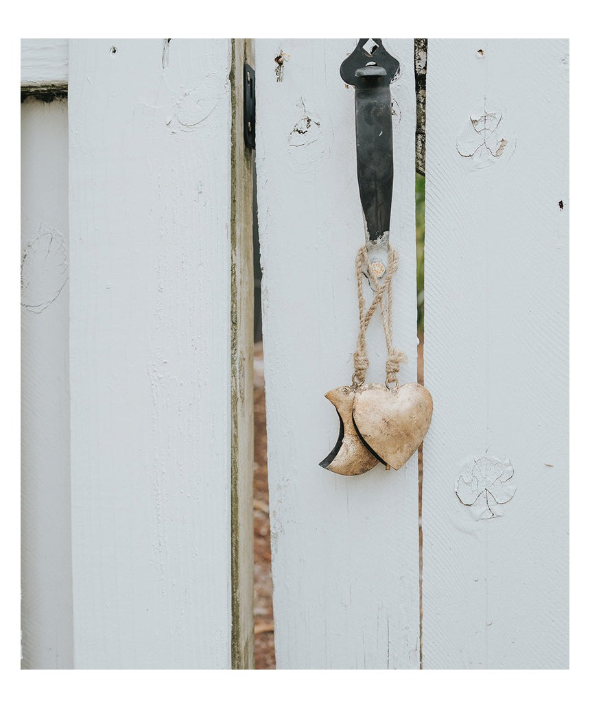 Matr Boomie Alaya Heart Wind Chime with metal and wood elements hanging from a string, designed to produce soothing sounds.