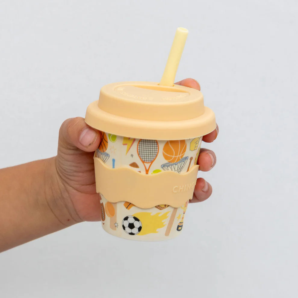 Hand holding a 4oz Chino Club Sports Baby Chino Cup, a small kids' cup with sporty design by Chino Club.