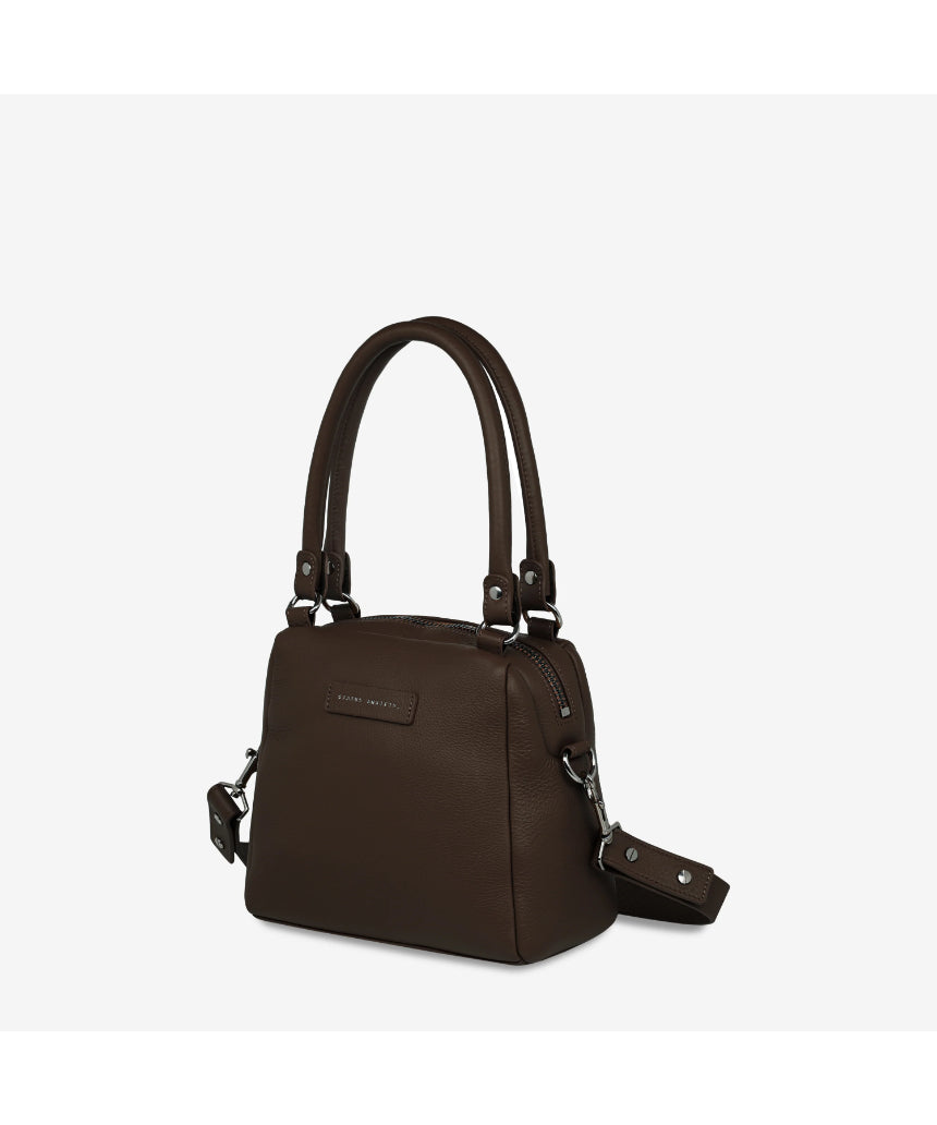 Status Anxiety Mini Mountains Bag in cocoa color, side front view showing compact bag with adjustable strap and mountain-inspired design.