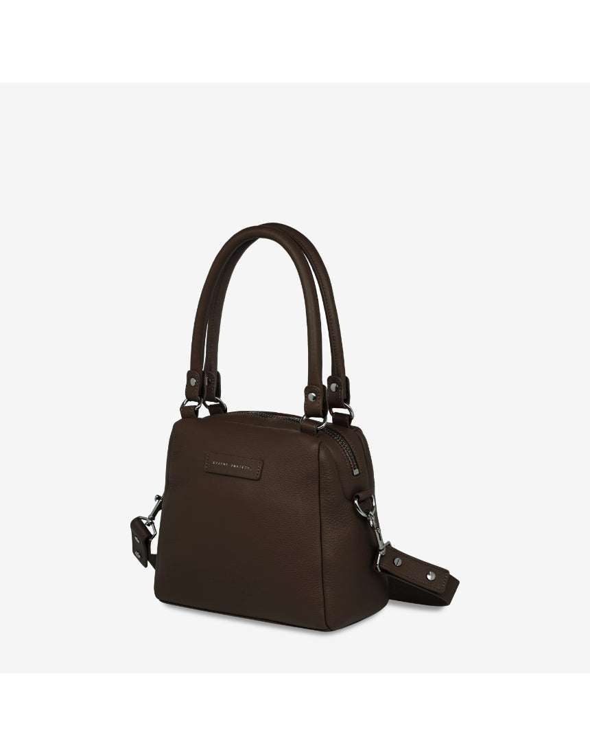 Status Anxiety Mini Mountains Bag in cocoa color, side front view showing compact bag with adjustable strap and mountain-inspired design.