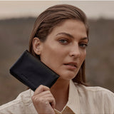 Black Status Anxiety Is Now Better Wallet with multiple card slots and sleek design, shown in a lifestyle setting.