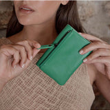 Status Anxiety Is Now Better Wallet in emerald green, featuring multiple card slots and a sleek, compact design.