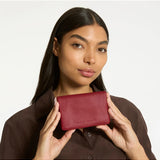 Status Anxiety Is Now Better Wallet in rouge color, featuring a sleek design with multiple card slots and a compact profile.