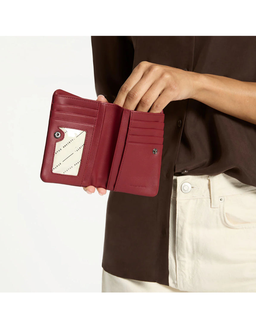 Status Anxiety Is Now Better Wallet in Rouge, featuring a sleek design and multiple card slots for stylish organization.