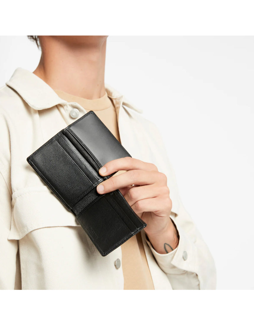 Black Status Anxiety Jonah Wallet with multiple card slots and cash compartments, shown in a lifestyle setting.