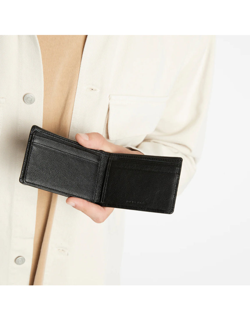 Black Status Anxiety Jonah Wallet with multiple card slots and sleek leather design, shown on a lifestyle background.