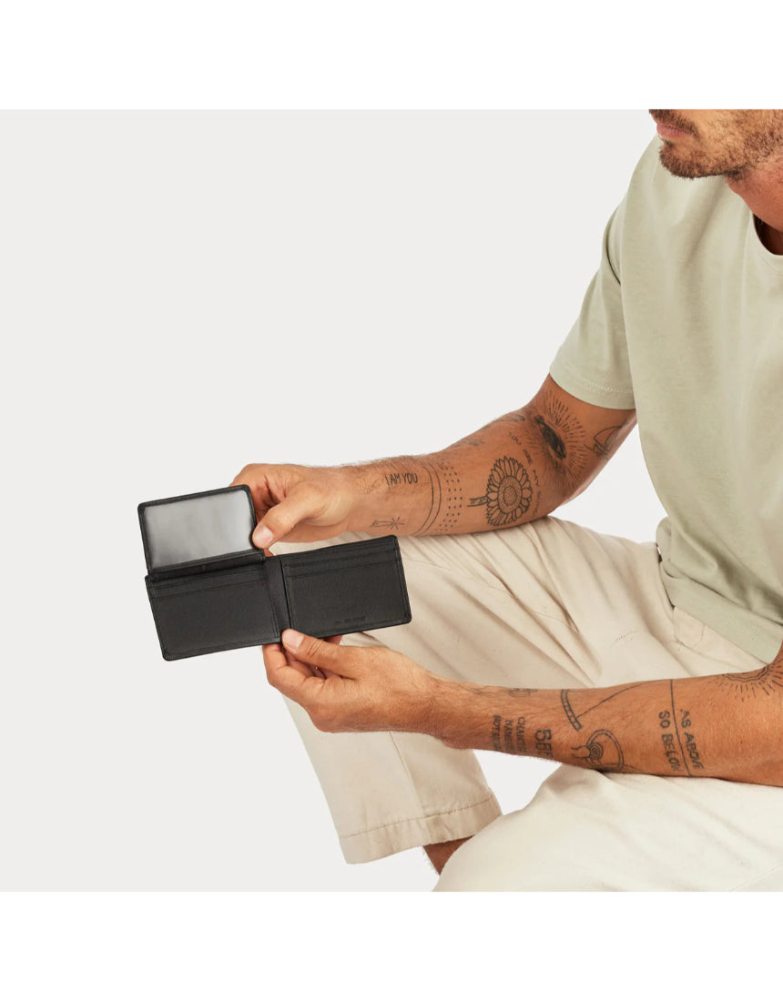 Black Status Anxiety Jonah Wallet with multiple card slots and a sleek leather design, displayed on a lifestyle background.