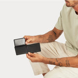 Black Status Anxiety Jonah Wallet with multiple card slots and a sleek leather design, displayed on a lifestyle background.