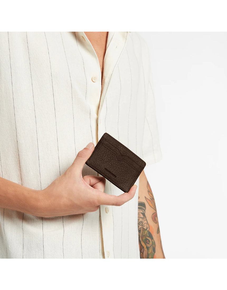 Status Anxiety Together For Now Cocoa wallet showing textured leather surface and stitched edges on a neutral background.
