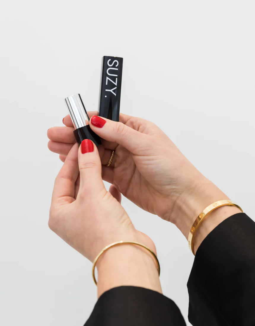 Suzy Lipsticks Miss Cassandra Peony Matte lipstick with a soft pink shade, shown in a sleek tube with the cap off.