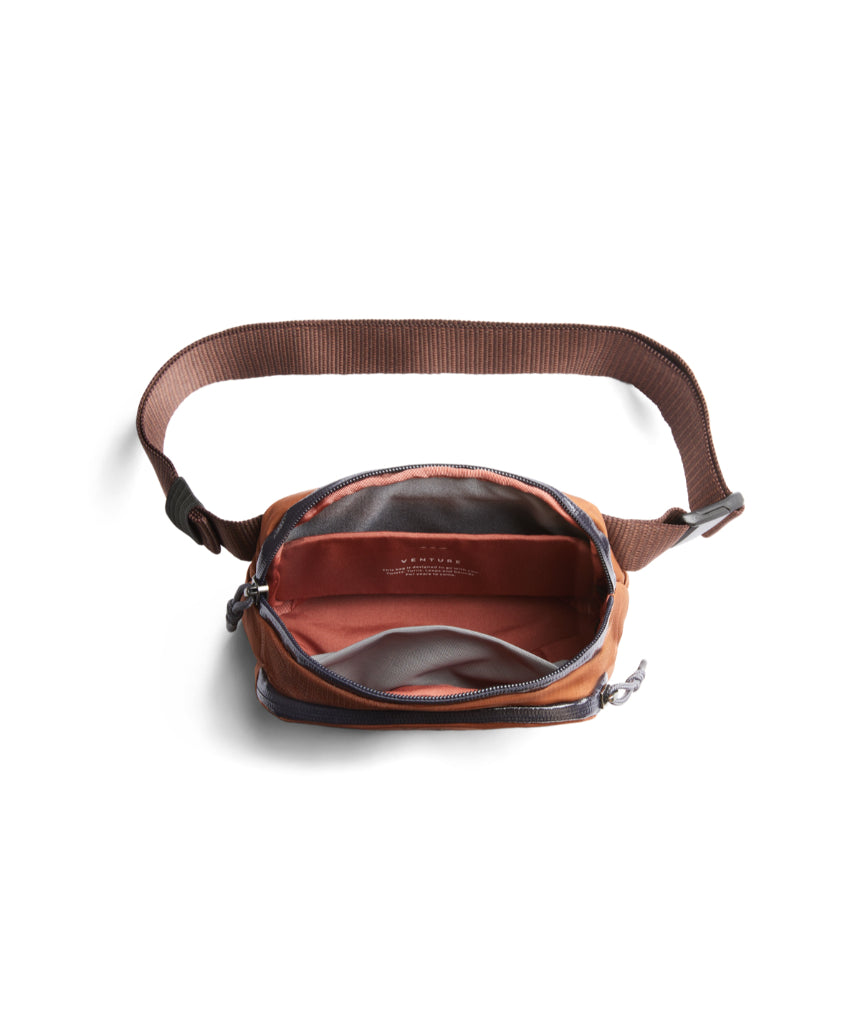 Bellroy Venture Hip Pack in bronze with multiple compartments, adjustable strap, and sleek design for convenient carrying.