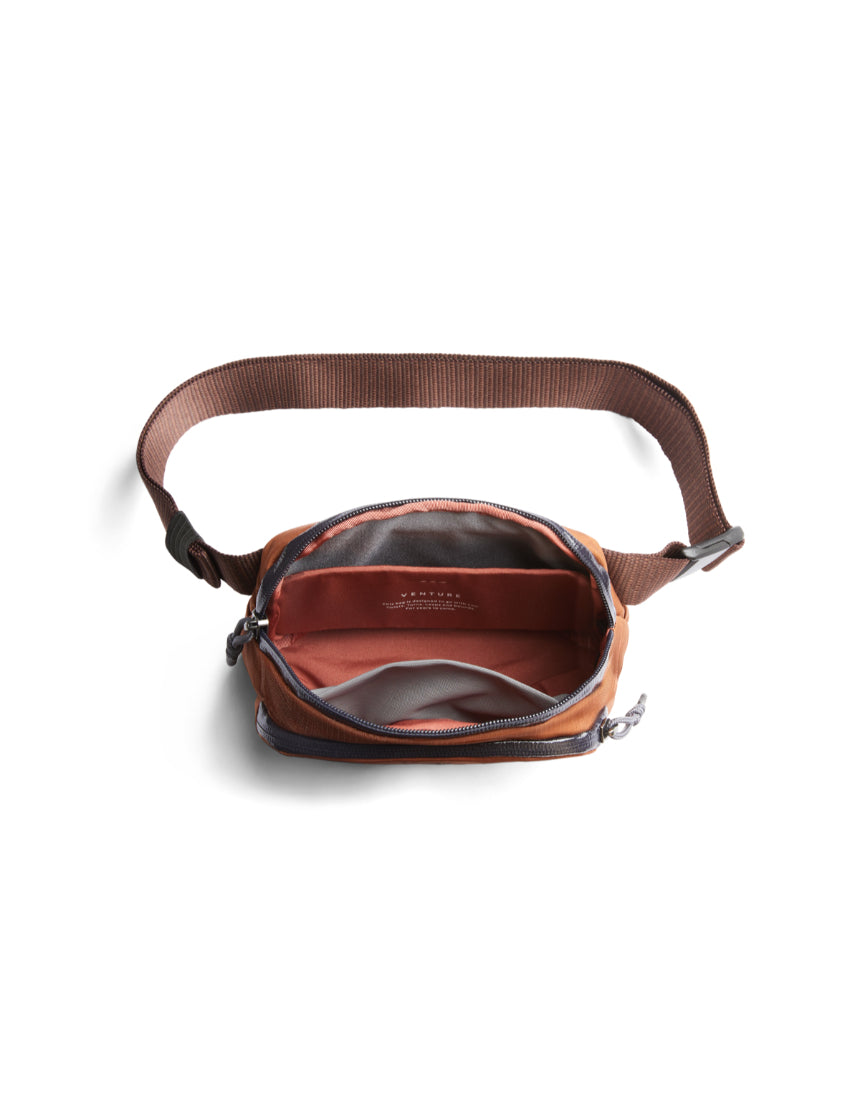 Bellroy Venture Hip Pack in bronze with multiple compartments, adjustable strap, and sleek design for convenient carrying.