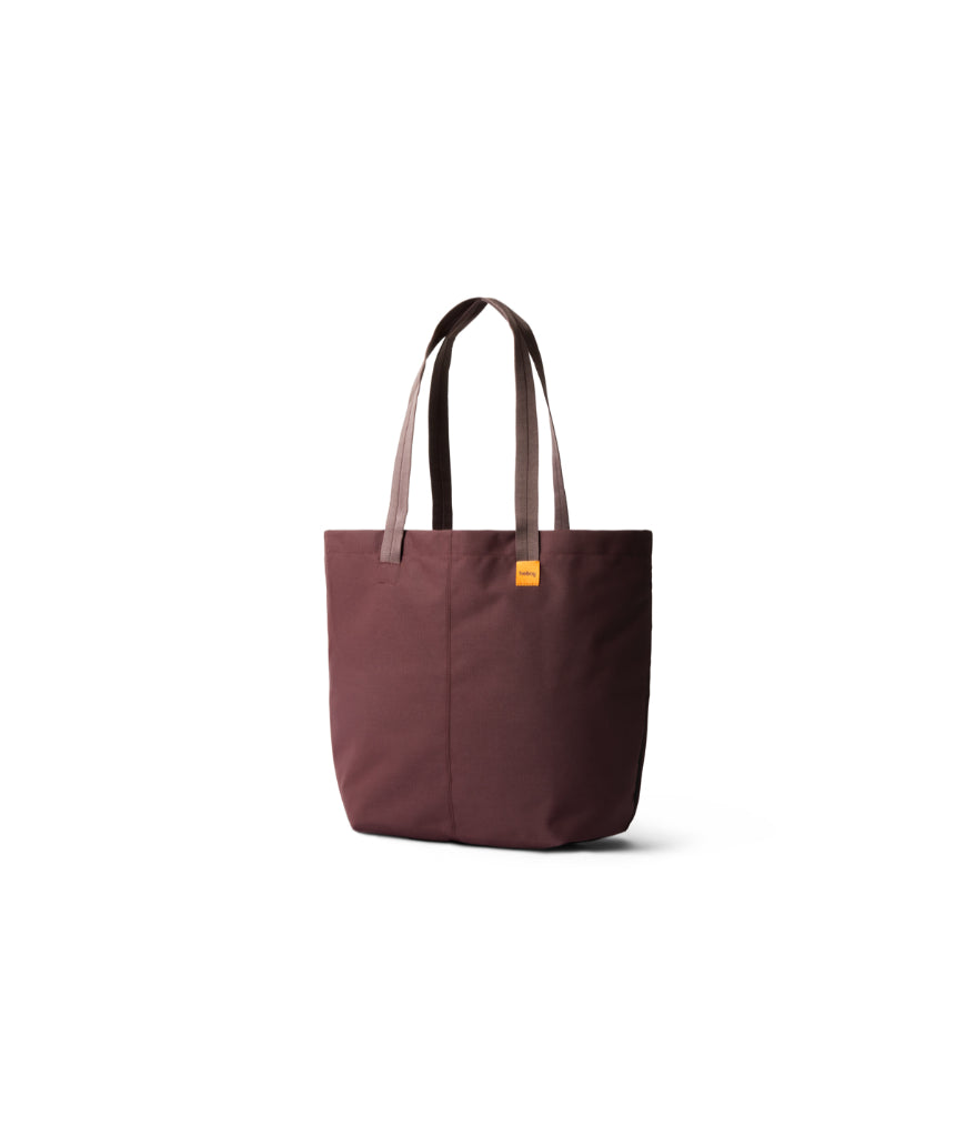 Bellroy Market Tote in burgundy fabric with leather handles, showing its spacious design and stylish craftsmanship.