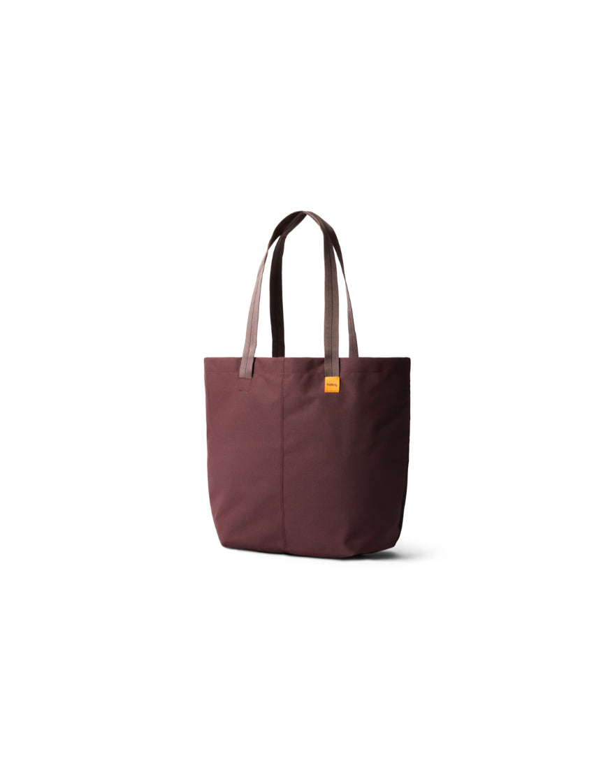 Bellroy Market Tote in burgundy fabric with leather handles, showing its spacious design and stylish craftsmanship.