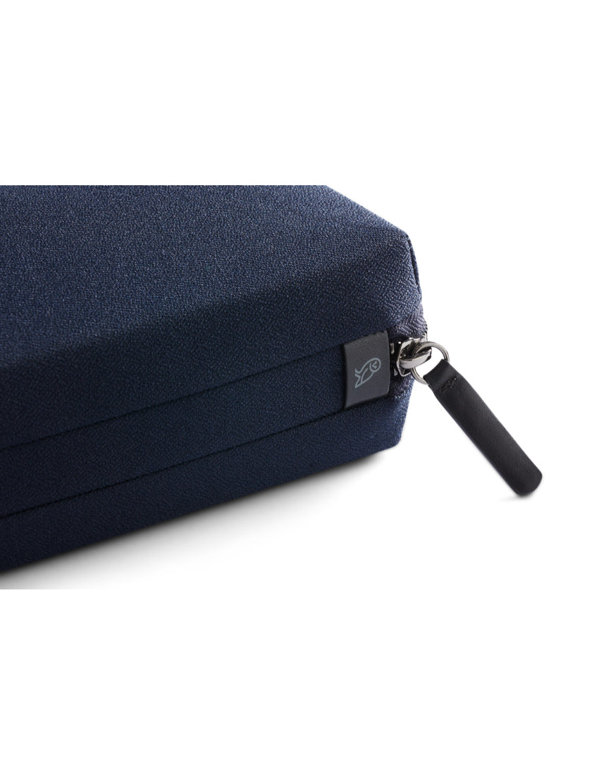 Bellroy Tech Kit in navy, compact organizer with multiple compartments for cables, chargers, and accessories, laid out on a surface.