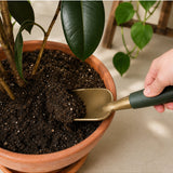 Green We The Wild hand trowel garden tool with a wooden handle and metal scoop for planting and gardening tasks.