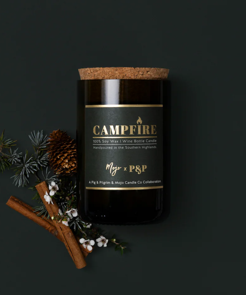 Mojo Candle Co. campfire scented candle in a glass jar, warm glow and cozy ambiance, perfect for relaxing or decorating.