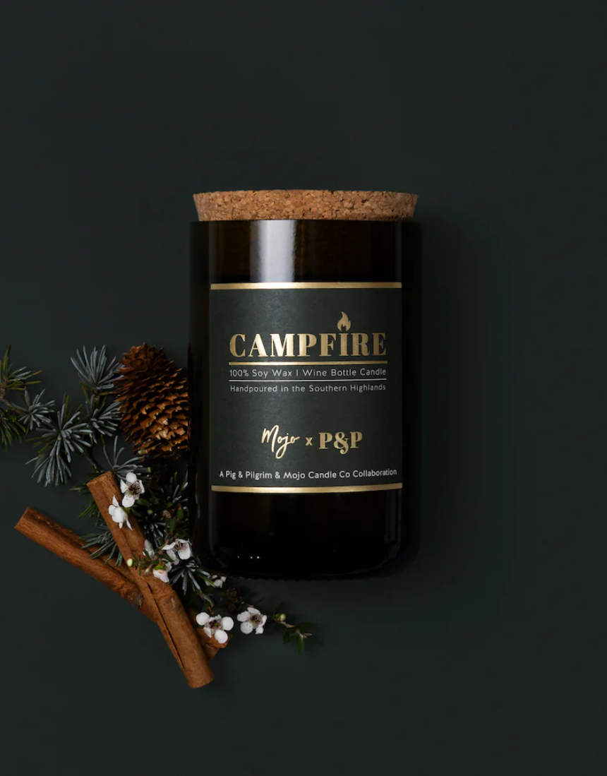 Mojo Candle Co. campfire scented candle in a glass jar, warm glow and cozy ambiance, perfect for relaxing or decorating.