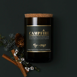 Mojo Candle Co. campfire scented candle in a glass jar, warm glow and cozy ambiance, perfect for relaxing or decorating.