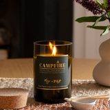 Mojo Candle Co. campfire scented candle in a glass jar, with a warm glow and wooden wick for cozy ambiance.