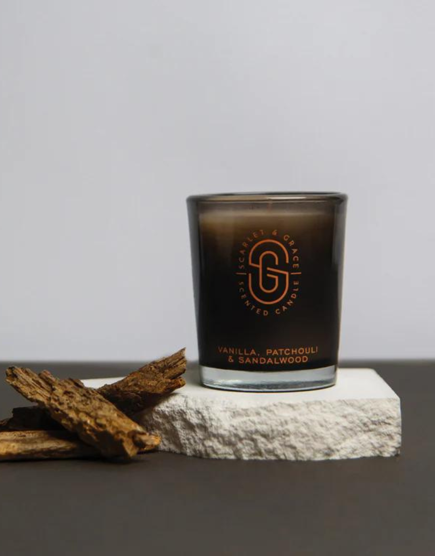 Scarlet & Grace vanilla, patchouli, and sandalwood scented candle in a 60g jar with a lit wick and elegant packaging.