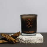 Scarlet & Grace vanilla, patchouli, and sandalwood scented candle in a 60g jar with a lit wick and elegant packaging.