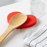 Fisura Heart-shaped spoon rest with a smooth ceramic finish, designed to hold and protect kitchen utensils during cooking.
