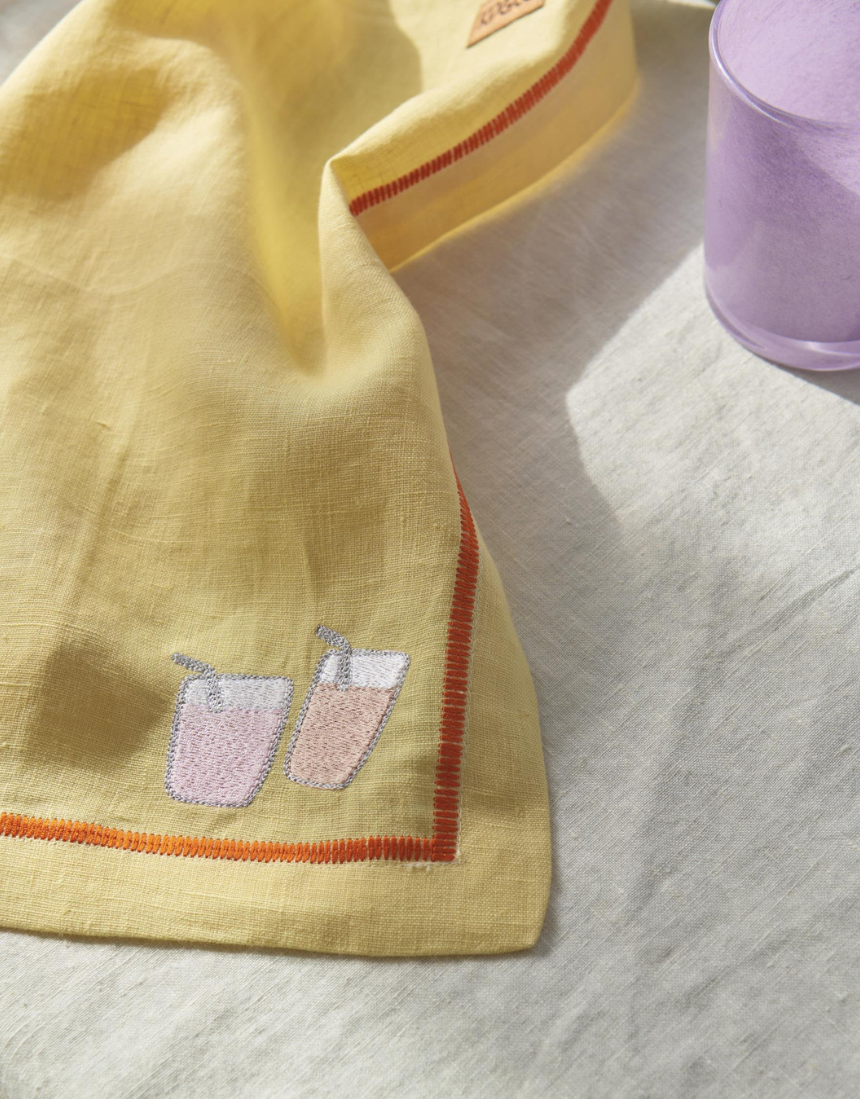 Kip & Co embroidered linen 4-piece breakfast napkin set with colorful "Breakfast Is Served" design and floral embroidery.