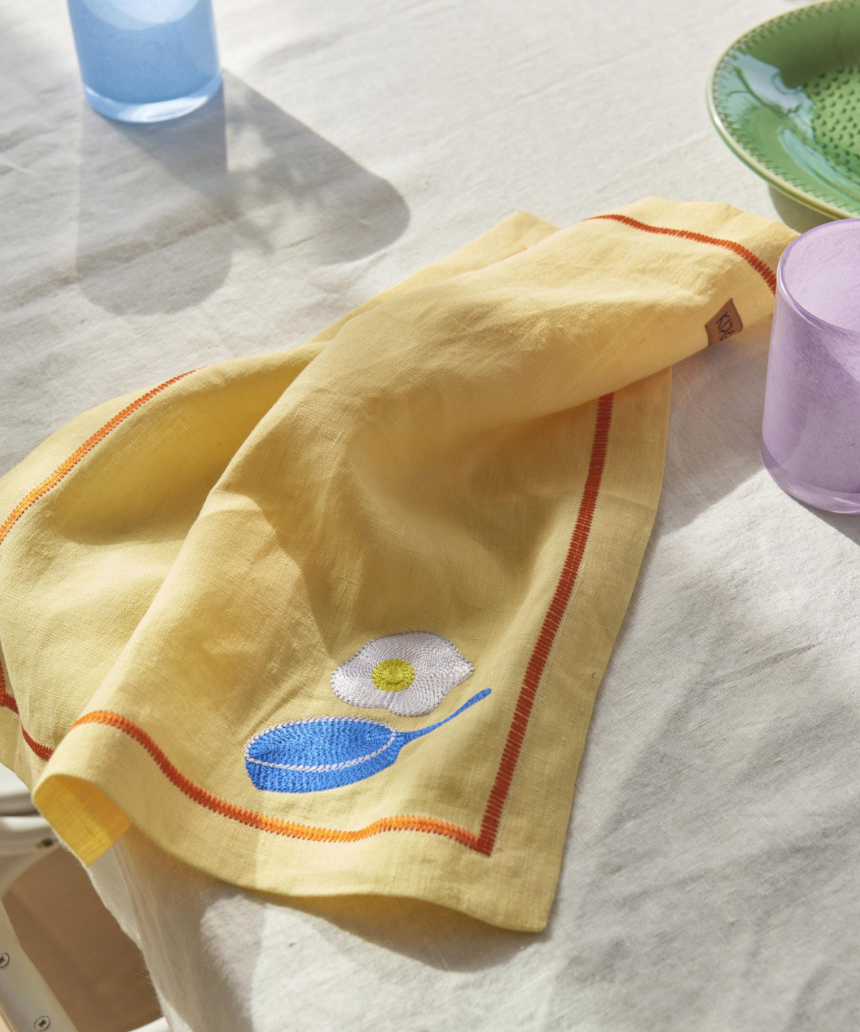 Kip & Co embroidered linen 4-piece breakfast napkin set with colorful "Breakfast Is Served" design on soft fabric.