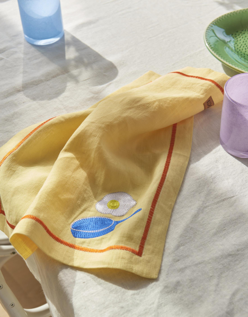 Kip & Co embroidered linen 4-piece breakfast napkin set with colorful "Breakfast Is Served" design on soft fabric.