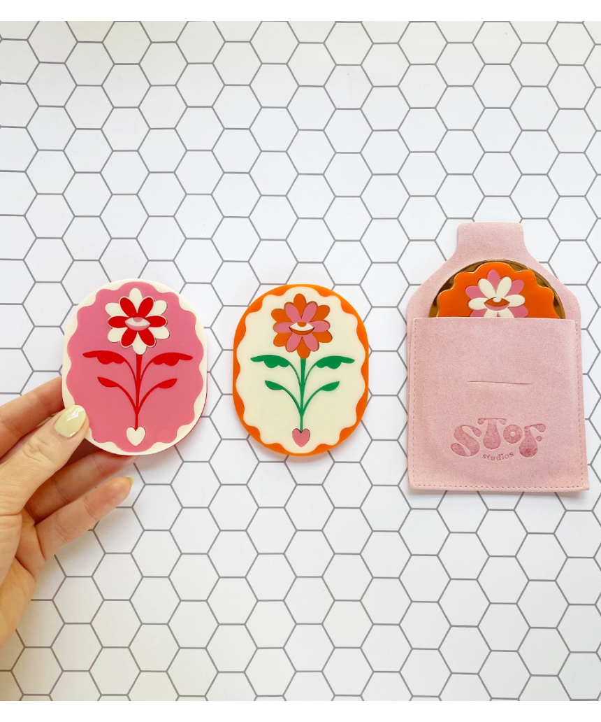 Stof Studios Eden Pocket Mirror in vibrant orange and gold with a sleek, compact design and reflective surface.