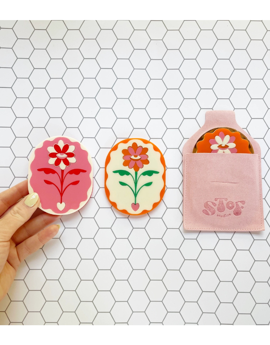 Stof Studios Eden Pocket Mirror in vibrant orange and gold with a sleek, compact design and reflective surface.