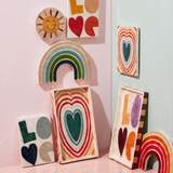 Jones & Co Golden Rainbow Pink wall decor featuring a colorful rainbow design on a neutral background.