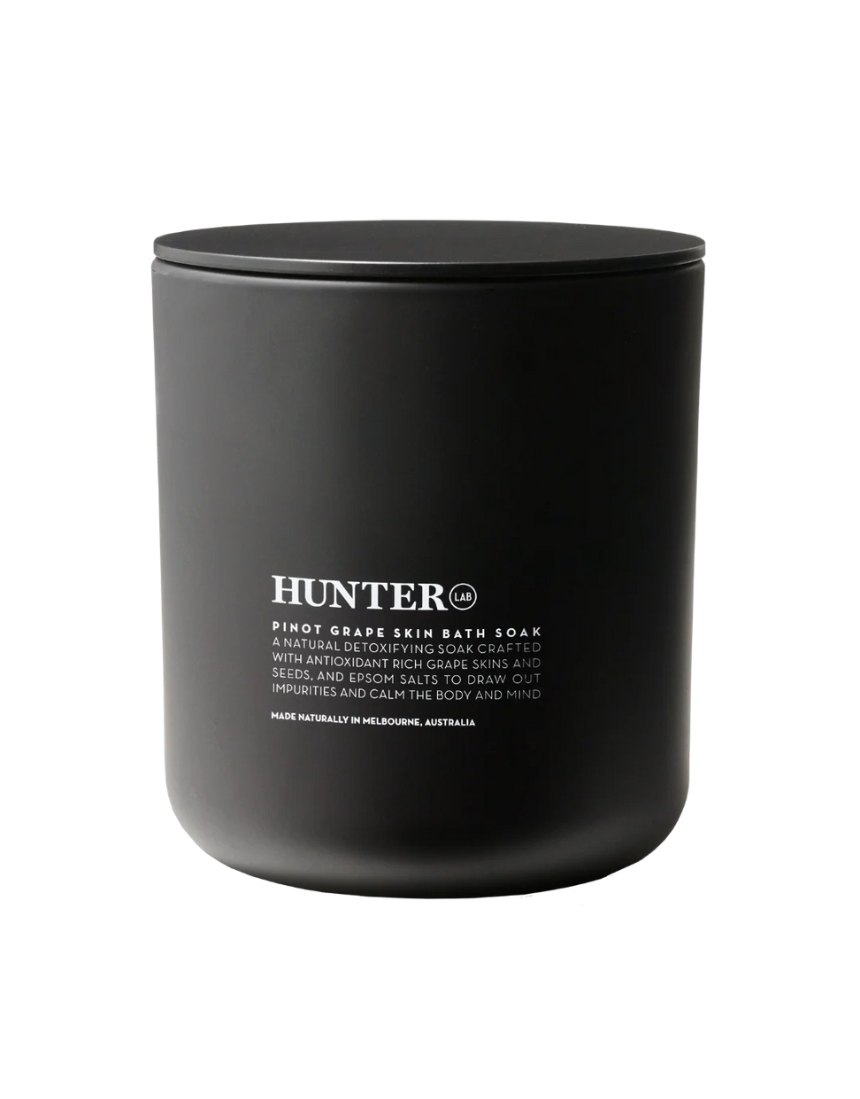 Hunter Lab Pinot Grape Skin Bath & Body soak with purple liquid in a clear glass jar, highlighting natural skincare ingredients